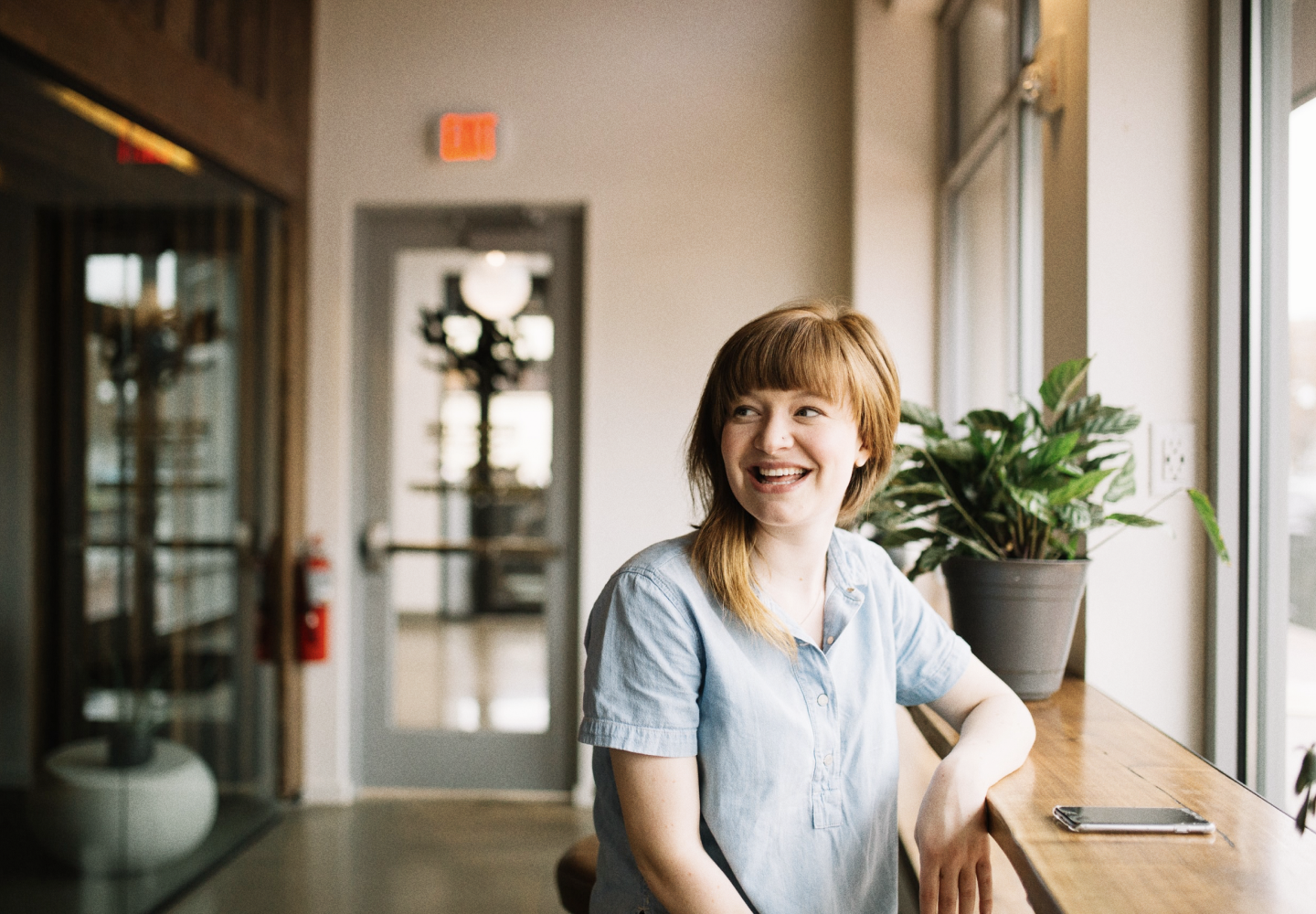 Mujer sonriendo apoyada en una mesa